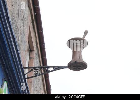 Mortier et pilon en bois suspendus en hauteur sur le bâtiment de la pharmacie, avec espace de copie Banque D'Images