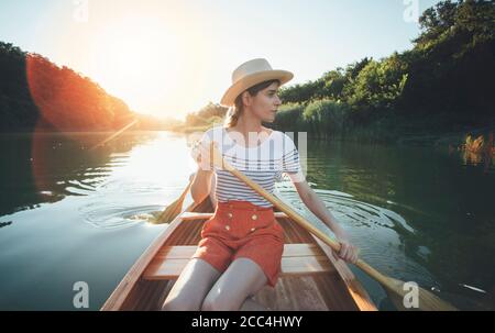 Jeune femme pagayer en canoë, couple profiter de la promenade en bateau sur le coucher du soleil d'été Banque D'Images