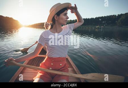 Jeune femme pagayer en canoë, couple profiter de la promenade en bateau sur le coucher du soleil d'été Banque D'Images