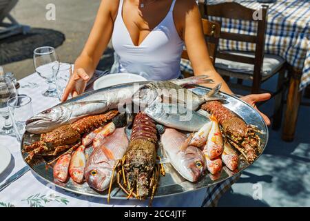 Belle, jeune femme choisit du poisson frais dans un restaurant de plage pour griller. Banque D'Images