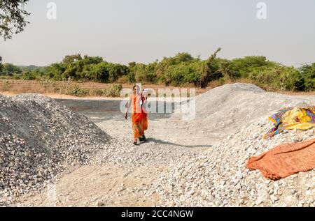 Puttaparthi, Andhra Pradesh, Inde - 11 janvier 2013 : une femme indienne marchant avec un panier de nourriture sur la pelouse du village de Puttaparthi. Banque D'Images