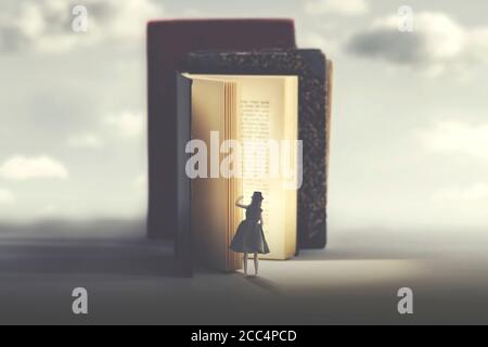 curieuse femme regarde dans un livre mystérieux illuminé Banque D'Images