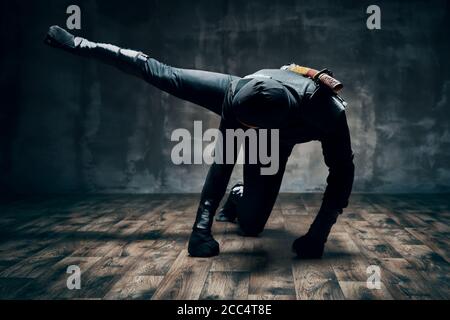 Ninja faisant des mouvements de combat coups de pied et de poinçonner avec la jambe sur fond noir. concept de combattant japonais Banque D'Images