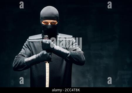 Combat ninja posant avec une épée sur fond noir. concept de combattant japonais Banque D'Images