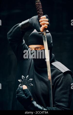 Combattant guerrier ninja samouraï avec une épée et shuriken sur fond noir. concept de combattant japonais Banque D'Images