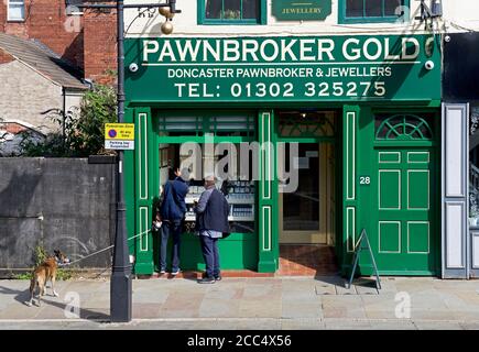 Deux hommes magasinent dans la boutique Pawnbroker Gold, Market place, Doncaster, South Yorkshire, Angleterre Banque D'Images