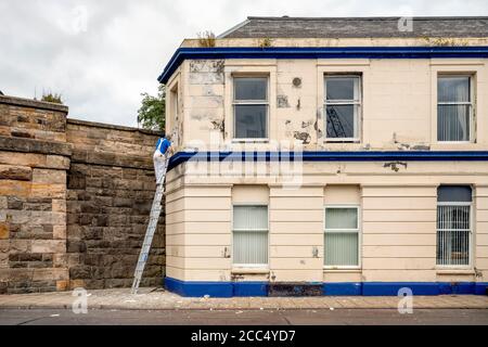 Peintre sur une échelle peint une maison. Banque D'Images