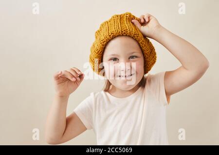 Portrait d'une petite fille avec le syndrome de Down portant un chapeau de laine et sourire à l'appareil photo isolé sur fond blanc Banque D'Images