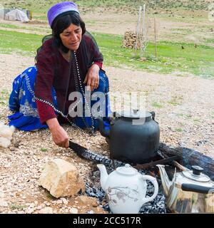 Qashqai femme de l'eau bouillante pour le thé, le camp nomade Qashqai, la province du Fars, Iran Banque D'Images