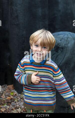 Jeune garçon (2/3 ans) jouant avec joie autour de 'Black Mound' par David Nash RA, Tremenheere Sculpture Garden, Penzance, Cornwall, Royaume-Uni. MODÈLE LIBÉRÉ Banque D'Images