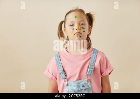 Portrait de l'enfant de syndrome de Down avec le visage peint regardant caméra isolée sur fond blanc Banque D'Images