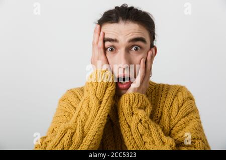 Portrait d'un homme stressé et choqué, avec contour d'oreille regardant et en touchant son visage sur fond blanc Banque D'Images