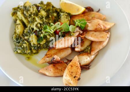 Calamars frits avec sauce de poisson et légumes sur une assiette blanche. Banque D'Images