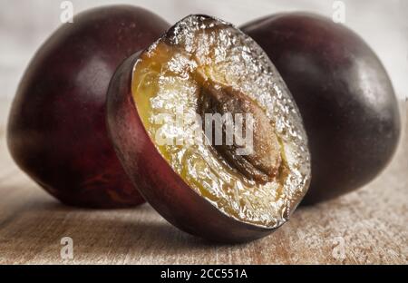 Deux prunes mûres et une demi-prune coupée avec un pierre Banque D'Images