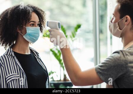 Mesure obligatoire de la fièvre sans contact thermomètre pistolet de tous les clients Banque D'Images