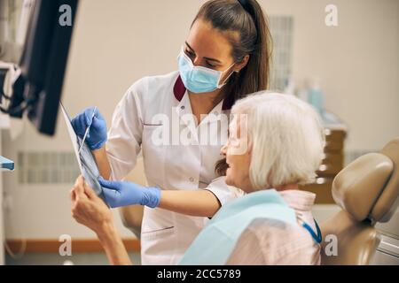 Belle femme vérifiant les dents après avoir pris soin des dents en clinique dentaire Banque D'Images