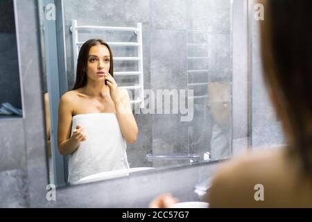 Reflet dans le miroir. Femme regarde dans le miroir de remarquer les premières rides Banque D'Images