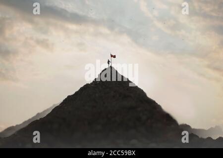 la femme plante son drapeau sur le sommet de la montagne comme un signe de réussite Banque D'Images