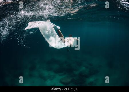 Femme Freediver avec des nageoires blanches glisse sous l'eau dans la mer transparente Banque D'Images