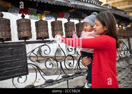 Une mère et son bébé tournent les roues de prière à Swayambhunath stupa à Katmandou, Népal. Banque D'Images