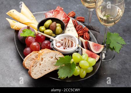 Assiette d'antipasti avec prosciutto, fromage, figues et raisins. Hors-d'œuvre et vin blanc Banque D'Images