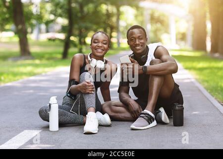 Couple africain sportif posant après l'entraînement en plein air, assis sur Path in Park Banque D'Images