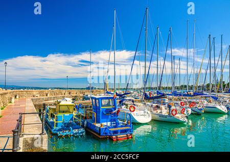 Desenzano del Garda, Italie, 11 septembre 2019: Jetée en pierre mole avec yachts sur le stationnement de bateau port marina et phare, ciel bleu blanc nuages fond, Lombardie Banque D'Images