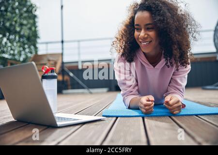 Belle dame avec des cheveux bouclés faisant de l'exercice physique à l'extérieur toit Banque D'Images