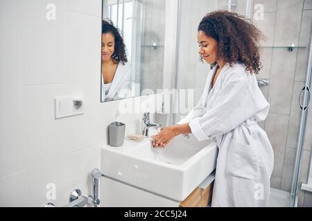 Femme se lavant les mains dans la salle de bains Banque D'Images