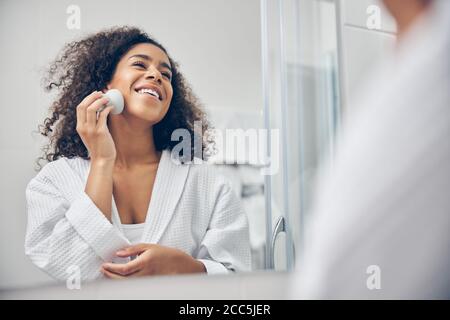 Femme hydratant sa peau avec un produit cosmétique Banque D'Images