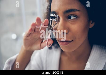 Femme sérieuse concentrée utilisant un fard à paupières Banque D'Images