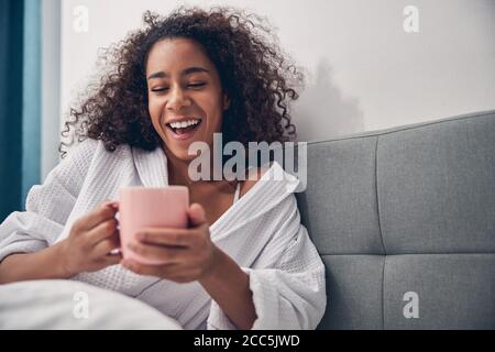 Une jolie dame riant avec cœur dans le lit aux cheveux sombres Banque D'Images