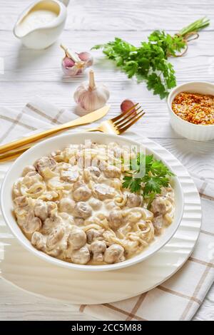 Gros plan de la sauce crémeuse aux champignons, des champignons sautés dans une sauce à la crème aigre servis dans un bol blanc, sur une table en bois, à la verticale Banque D'Images