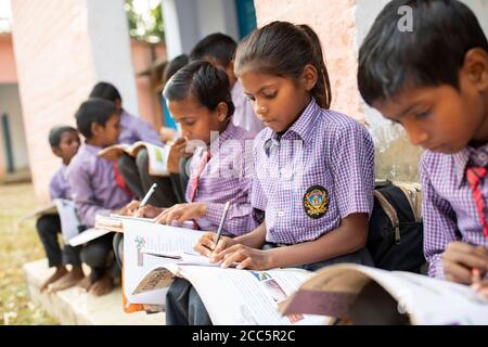 Les élèves de l'école primaire en uniforme fréquentent l'école ensemble et étudient avec des manuels et des instruments d'écriture à Bihar, en Inde. Banque D'Images