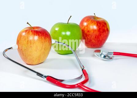 variété de pommes fraîches avec stéthoscope médical sur blanc Banque D'Images