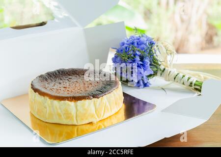 Le basque brûla cheesecake avec un bouquet d'hydraange sur une table en bois. Banque D'Images