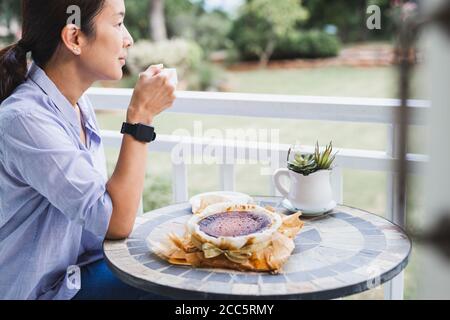 Femme ayant un café et un gâteau spécial sur la table célébration de quarantaine à la maison Banque D'Images