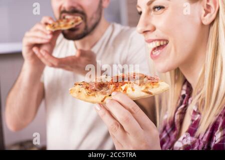 Un couple heureux de manger sa pizza maison et délicieuse dans le cuisine Banque D'Images
