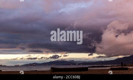 Un magnifique coucher de soleil sur la plage de la baie anglaise à Vancouver Canada, mettant en vedette le ciel avec les nuages et le coucher de soleil coloré et les ferries de cargaison Banque D'Images