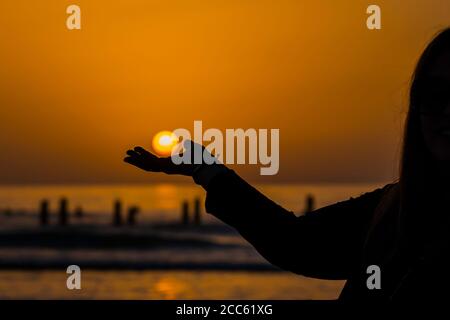 Coucher de soleil sur la mer. Le soleil dans la paume de sa main Banque D'Images