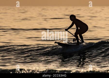 Silhouette de surfeurs dans la mer Méditerranée au coucher du soleil . Photographié sur la plage de Beit Yanai, Israël Banque D'Images