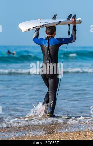 Surfeur avec planche de surf entrer dans la mer Méditerranée photographié à Beit Yanai, Israël Banque D'Images