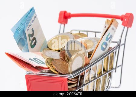 Panier plein de pièces et billets en euros, fond blanc. Concepts de valeur monétaire, d'inflation et de pouvoir d'achat Banque D'Images