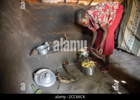 Une réfugiée sud-soudanaise qui cuisine sur un poêle à bois à faible consommation de carburant dans sa petite cuisine dans le camp de réfugiés de Palabek, dans le nord de l'Ouganda, en Afrique de l'est. Banque D'Images