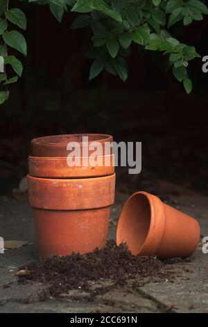 Quatre pots de terre cuite vides sur le patio en ardoise avec foncé arrière-plan Banque D'Images