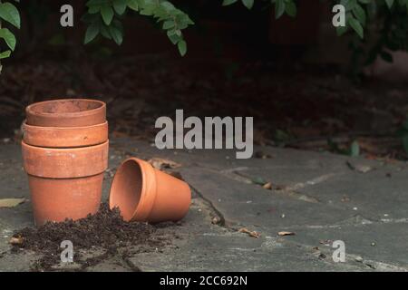 Quatre pots de terre cuite vides sur le patio en ardoise avec foncé arrière-plan Banque D'Images