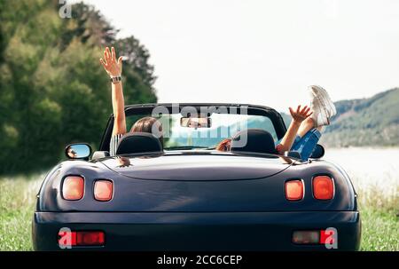 Deux filles voyageurs s'assoient dans une voiture cabriolet et aiment avec belle vue Banque D'Images