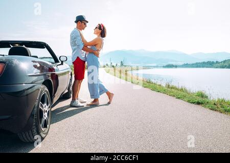 Un couple amoureux se tient près de la voiture cabriolet la route pittoresque de montagne Banque D'Images