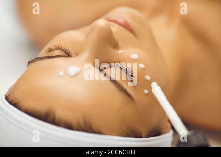 Cosmétologue faisant le traitement de la peau avec hydratant pour la jeune femme de patient dans le salon de beauté Banque D'Images