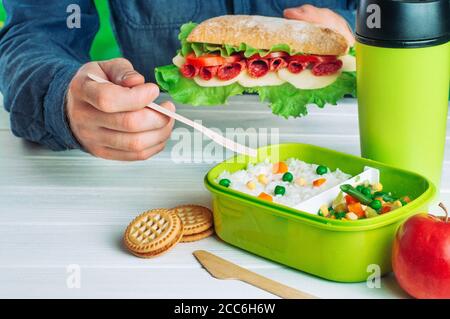 Les mâles mangeaient le sandwich et le riz avec des légumes mélangés de sa boîte à lunch Banque D'Images